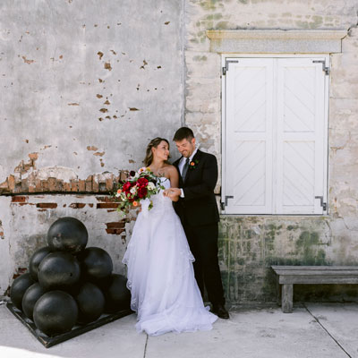 photo of a bride and groom next to canon balls at fort zach